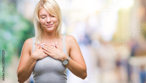 Young beautiful blonde woman over isolated background smiling with hands on chest with closed eyes and grateful gesture on face. Health concept. © Krakenimages.com