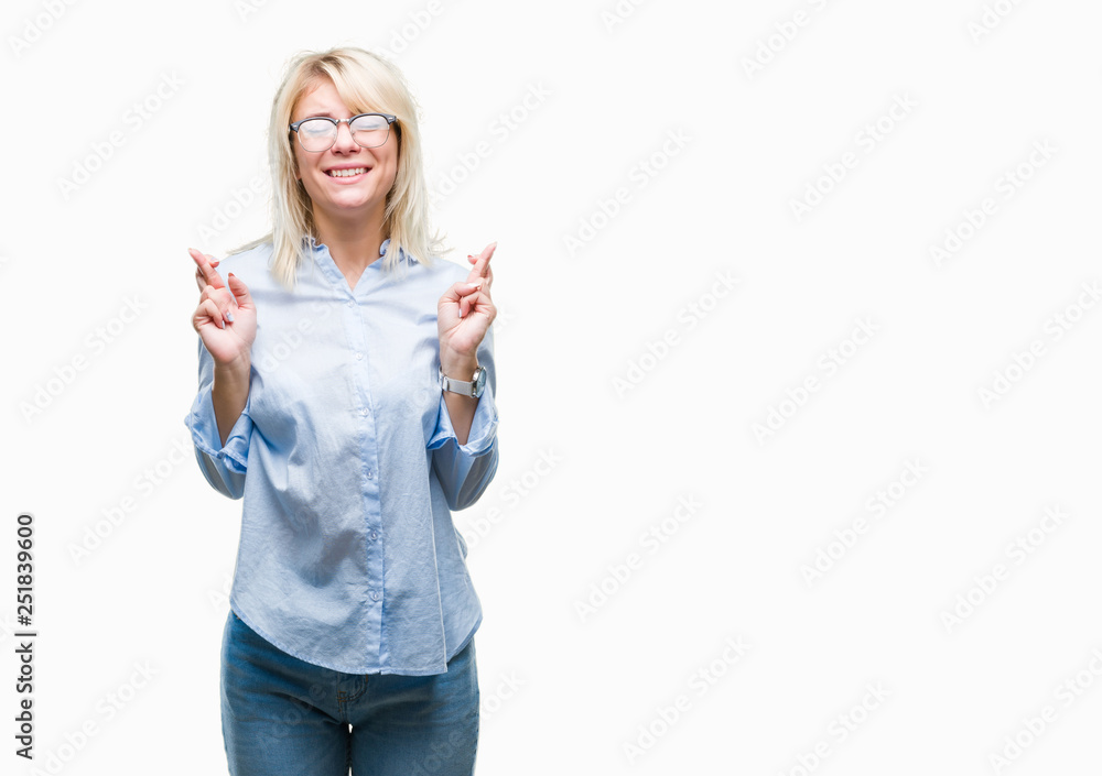 Young beautiful blonde business woman wearing glasses over isolated background smiling crossing fingers with hope and eyes closed. Luck and superstitious concept. Young beautiful blonde business woman wearing glasses over isolated background smiling crossing fingers with hope and eyes closed. Luck and superstitious concept.