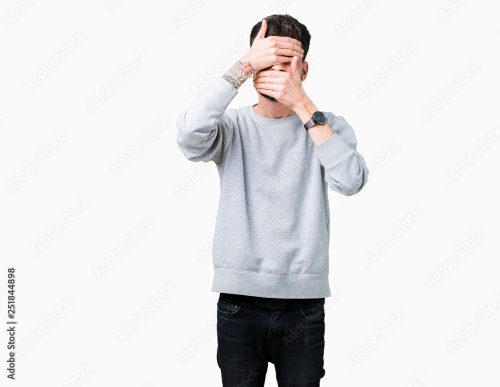 Young handsome man wearing sweatshirt over isolated background Covering eyes and mouth with hands, surprised and shocked. Hiding emotion Young handsome man wearing sweatshirt over isolated background Covering eyes and mouth with hands, surprised and shocked. Hiding emotion