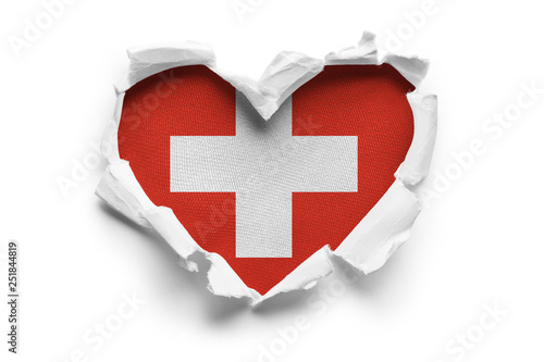 Heart shaped hole torn through paper, showing satin texture of flag of Switzerland. Isolated on white background photo