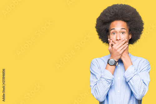 Young african american man with afro hair shocked covering mouth with hands for mistake. Secret concept.