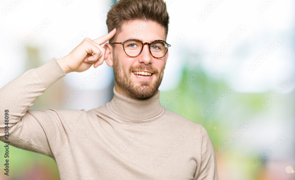 Young handsome business man wearing glasses Smiling pointing to head with one finger, great idea or thought, good memory Young handsome business man wearing glasses Smiling pointing to head with one finger, great idea or thought, good memory
