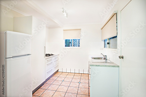 Compact white fitted kitchen with tiled floor