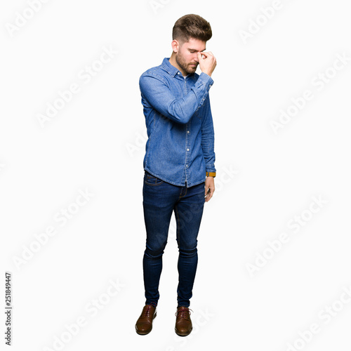 Young handsome blond man wearing casual denim shirt tired rubbing nose and eyes feeling fatigue and headache. Stress and frustration concept. © Krakenimages.com