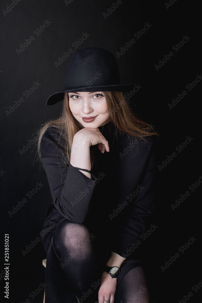 portrait of a young girl in a black dress and a hat on a dark background in the studio portrait of a young girl in a black dress and a hat on a dark background in the studio