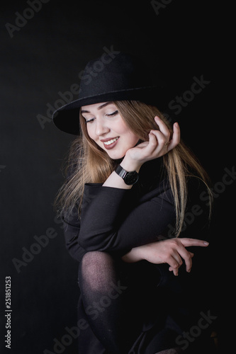 portrait of a young girl in a black dress and a hat on a dark background in the studio © Андрей Пугачев