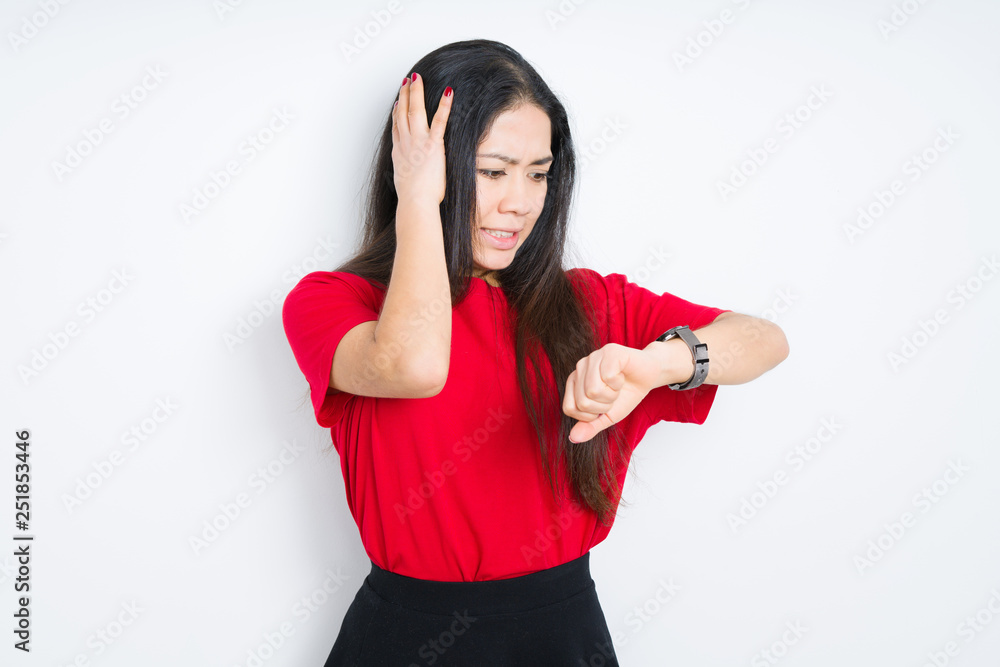 Beautiful brunette woman wearing red t-shirt over isolated background Looking at the watch time worried, afraid of getting late Beautiful brunette woman wearing red t-shirt over isolated background Looking at the watch time worried, afraid of getting late