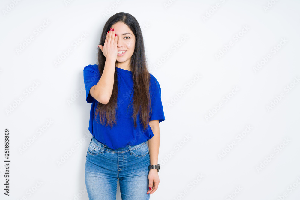 Beautiful brunette woman over isolated background covering one eye with hand with confident smile on face and surprise emotion. Beautiful brunette woman over isolated background covering one eye with hand with confident smile on face and surprise emotion.