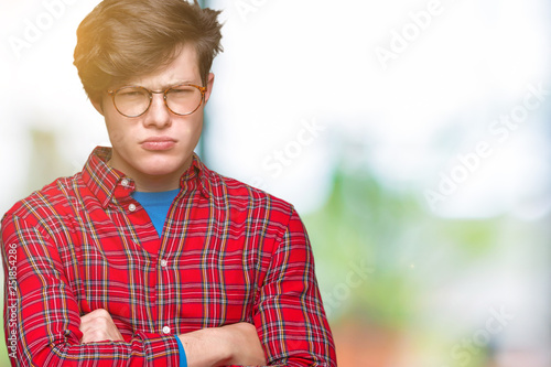 Young handsome man wearing glasses over isolated background skeptic and nervous  disapproving expression on face with crossed arms. Negative person.
