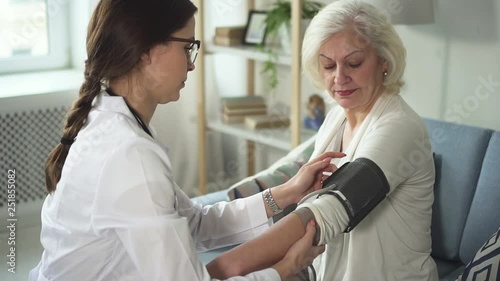Wallpaper Mural Concept of qualified support. Experienced and professional practitioner measuring blood pressure to her aged patient. They sitting inside light, bright living room Torontodigital.ca