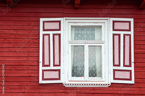 Red paint wooden rustic window in small cottage house. Vintage wall with transparent glass window and decorative red and white shutter. © Paweł Michałowski