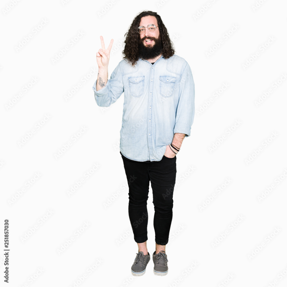Young hipster man with long hair and beard wearing glasses showing and pointing up with fingers number two while smiling confident and happy. Young hipster man with long hair and beard wearing glasses showing and pointing up with fingers number two while smiling confident and happy.