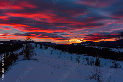 Magnificent landscape of the Carpathian Mountains at dawn with bright red clouds