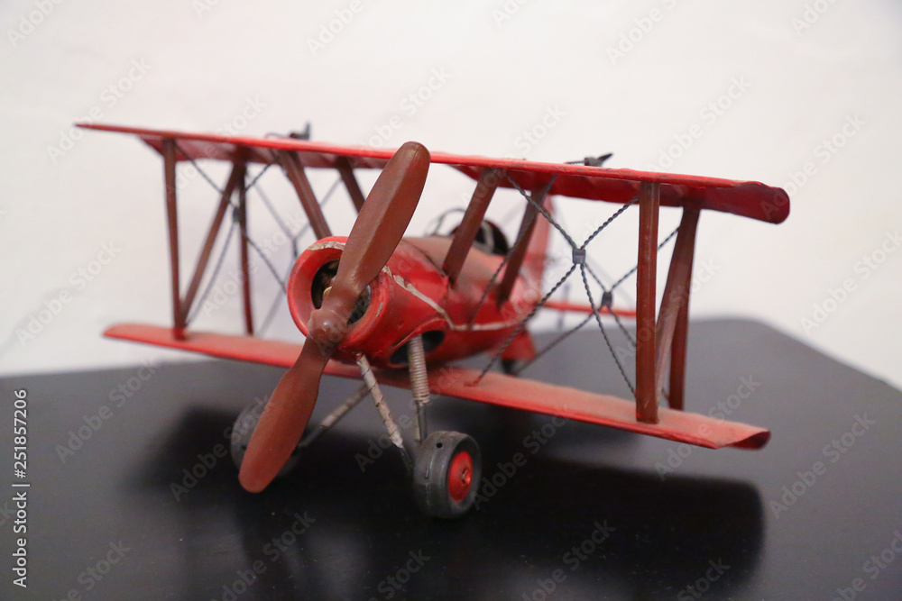 model of a red biplane aircraft with propeller driven engine on a black desk in front of white background isolated model of a red biplane aircraft with propeller driven engine on a black desk in front of white background isolated