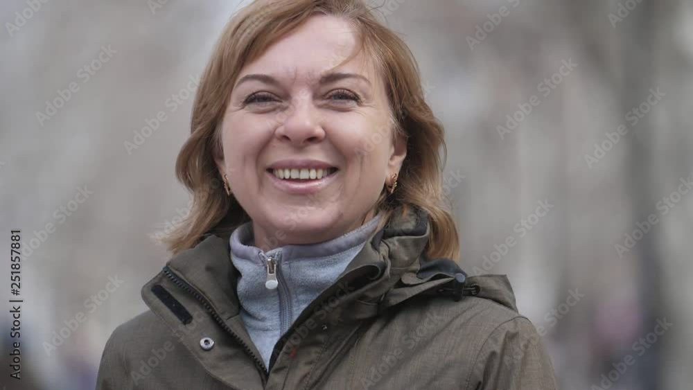 Cheery blond woman in a hoodie smiling and standing in alley in winter in slo-mo Cheery blond woman in a hoodie smiling and standing in alley in winter in slo-mo
