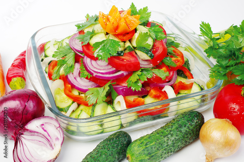 Vegetable salad in a transparent salad bowl. Tomatoes, cucumbers, onions, peppers, parsley. © yrafoto