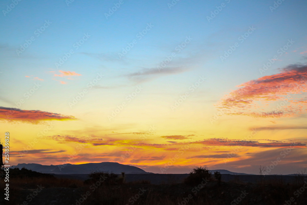 all colors colours orange red purple blue sunset sky over hilly landscape steppe