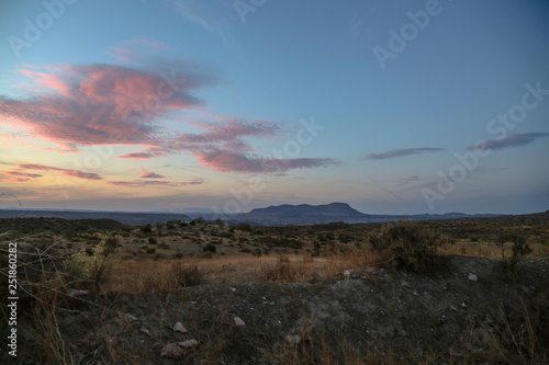 sunset over the mountains with clear blue sky and purple clouds over a steppe grassland