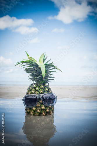 Fresh tropical exotic pineapple fruit with sunglasses on the beach