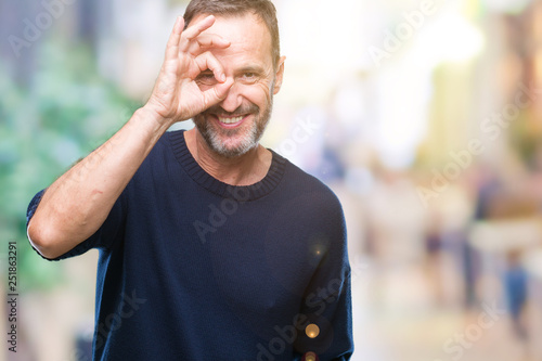 Middle age hoary senior man over isolated background doing ok gesture with hand smiling, eye looking through fingers with happy face.