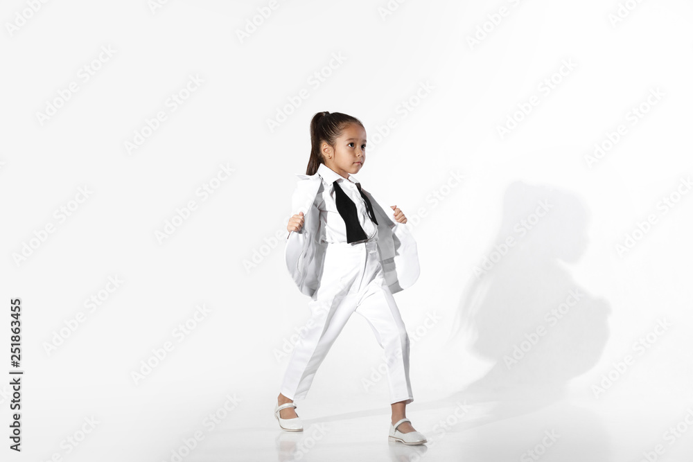 fashion beautiful little girl model in a white suit and untied bow tie on white background. fashion child concept