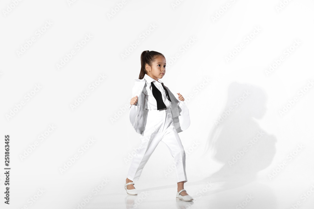 fashion beautiful little girl model in a white suit and untied bow tie on white background. fashion child concept fashion beautiful little girl model in a white suit and untied bow tie on white background. fashion child concept