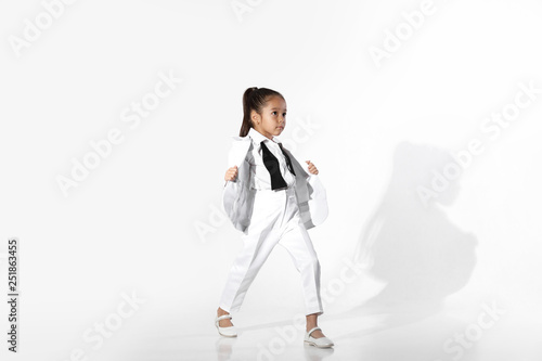 fashion beautiful little girl model in a white suit and untied bow tie on white background. fashion child concept