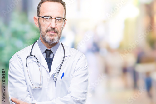 Middle age senior hoary doctor man wearing medical uniform isolated background with serious expression on face. Simple and natural looking at the camera.