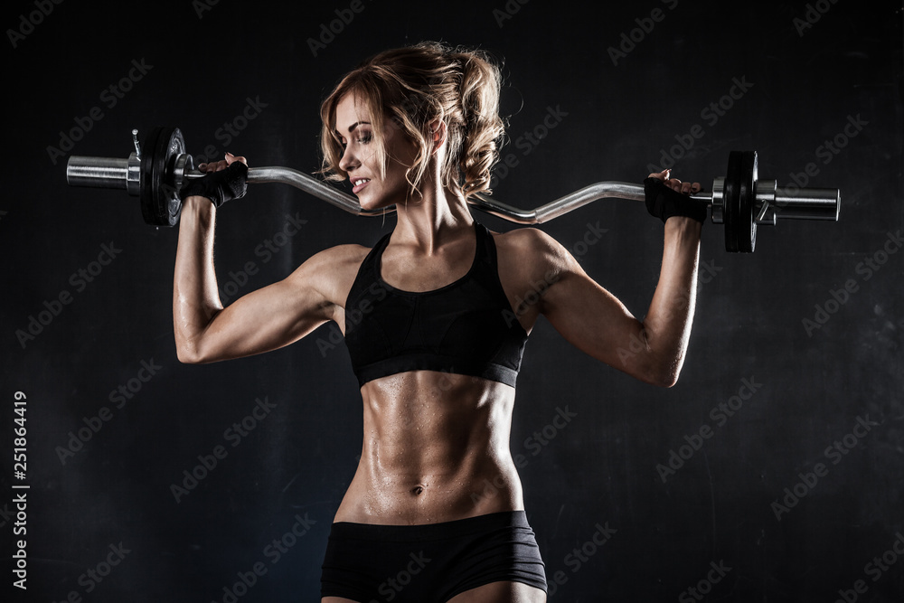 beautiful athletic woman makes exercises with barbell