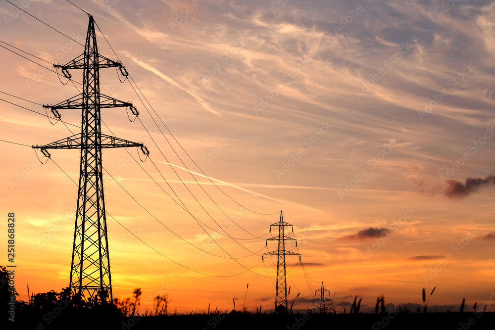 sunset with electricity tower in countryside. Summer  scene. Dusk sky with sun. Spring sunset