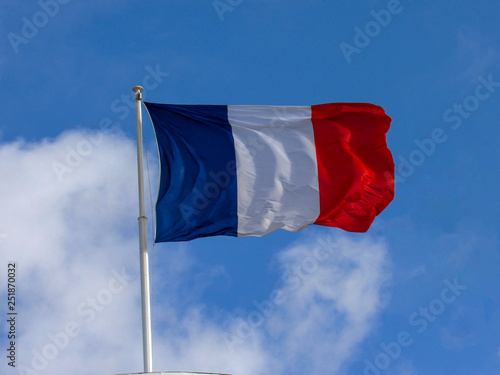 Traditional texture fabric tricolor French flag waving in the wind with natural blue sky background