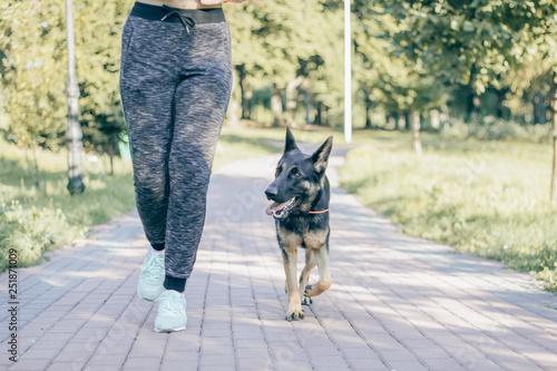 woman jogging in the park with a German shepherd