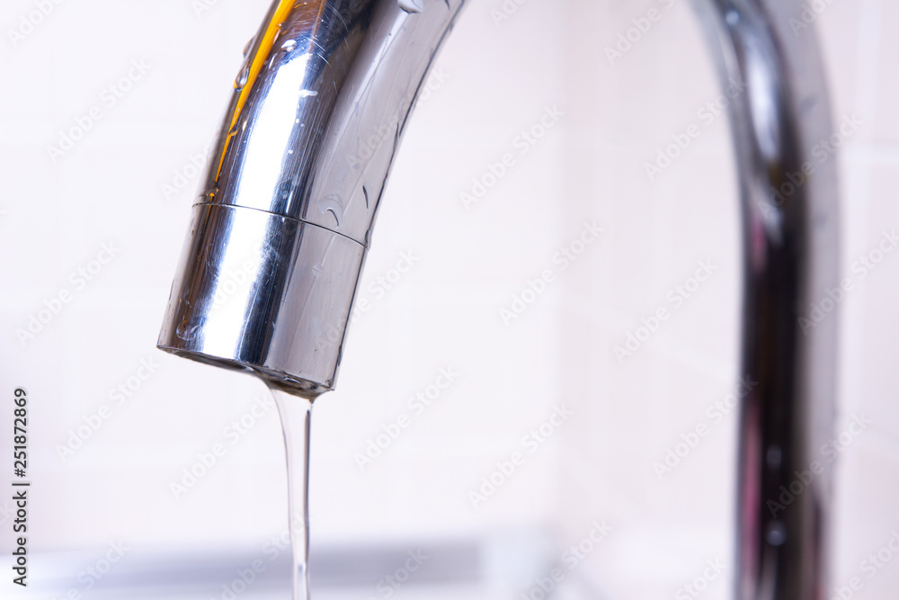 Jet of water pouring from tap. Faucet with water drop close-up Jet of water pouring from tap. Faucet with water drop close-up