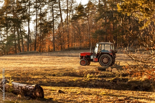 Old red tractor on the edge of a forest. Work in forest. An abandoned tractor. Landscape of the Czech countryside.