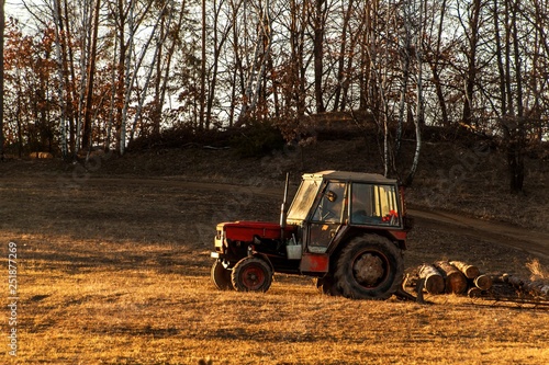 Old red tractor on the edge of a forest. Work in forest. An abandoned tractor. Landscape of the Czech countryside.