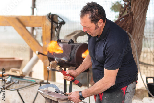 Blacksmith working on the anvil, making a horseshoe . © herraez