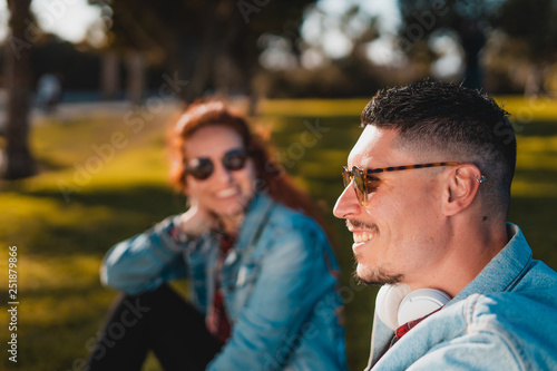 Happy young couple in love talking while sitting in a green park