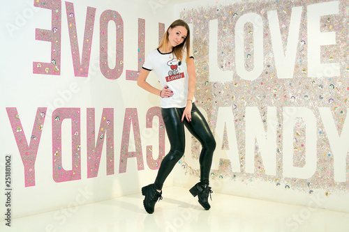 Konstfotografi Sport looking girl in the white T-shirt and black skinny tights poses on the colored background