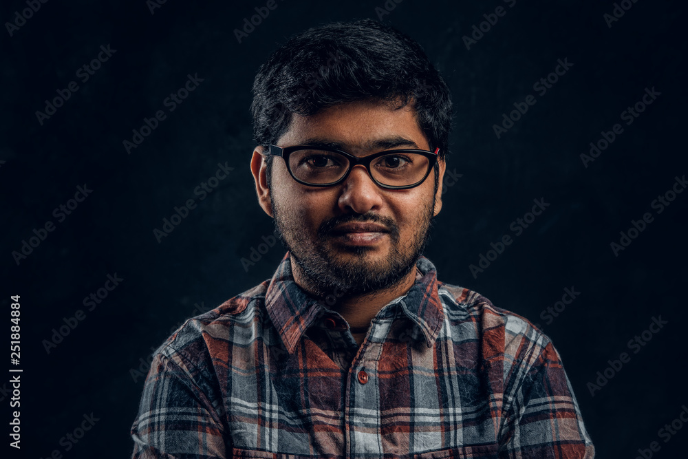 Portrait of a dark skinned chubby guy looking into a camera in a studio on a black background Portrait of a dark skinned chubby guy looking into a camera in a studio on a black background