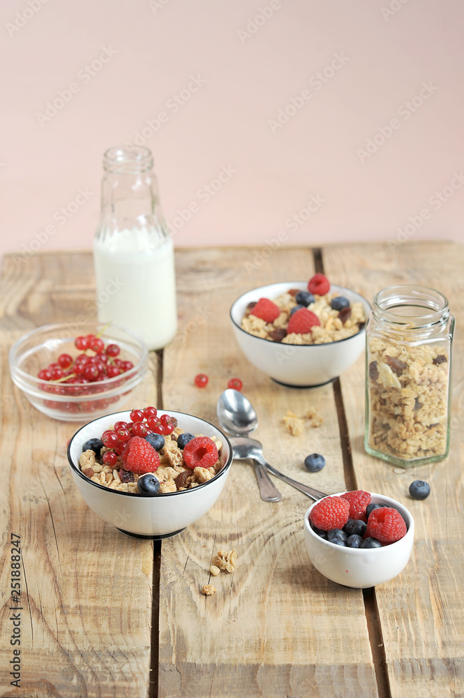 The concept of a healthy breakfast. Granola with berries, with milk and cutlery. Light wooden background. Vertical frame orientation. The concept of a healthy breakfast. Granola with berries, with milk and cutlery. Light wooden background. Vertical frame orientation.