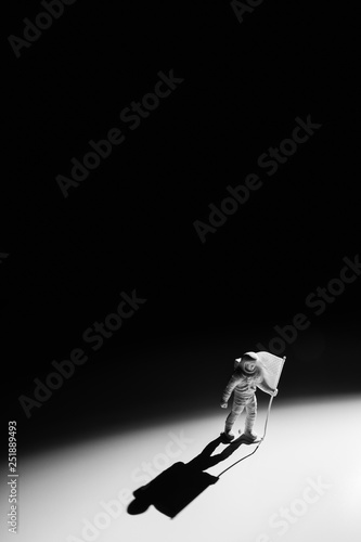 Fototapeta Naklejka Na Ścianę i Meble -  Lone Generic White Astronaut Figurine with American Flag in dramatic lighting