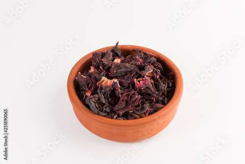 petals of dry hibiscus tea in the clay pot isolated on white background, top view