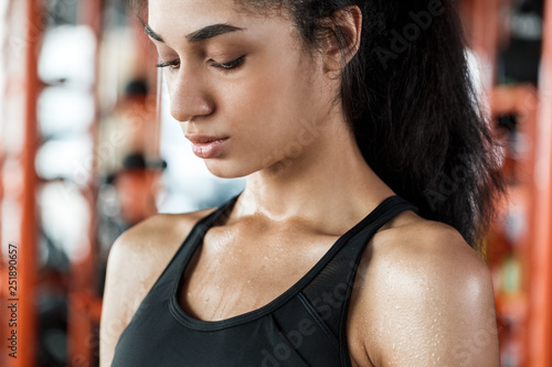 Young woman in gym sporty lifestyle standing close-up sweating breathing tough training