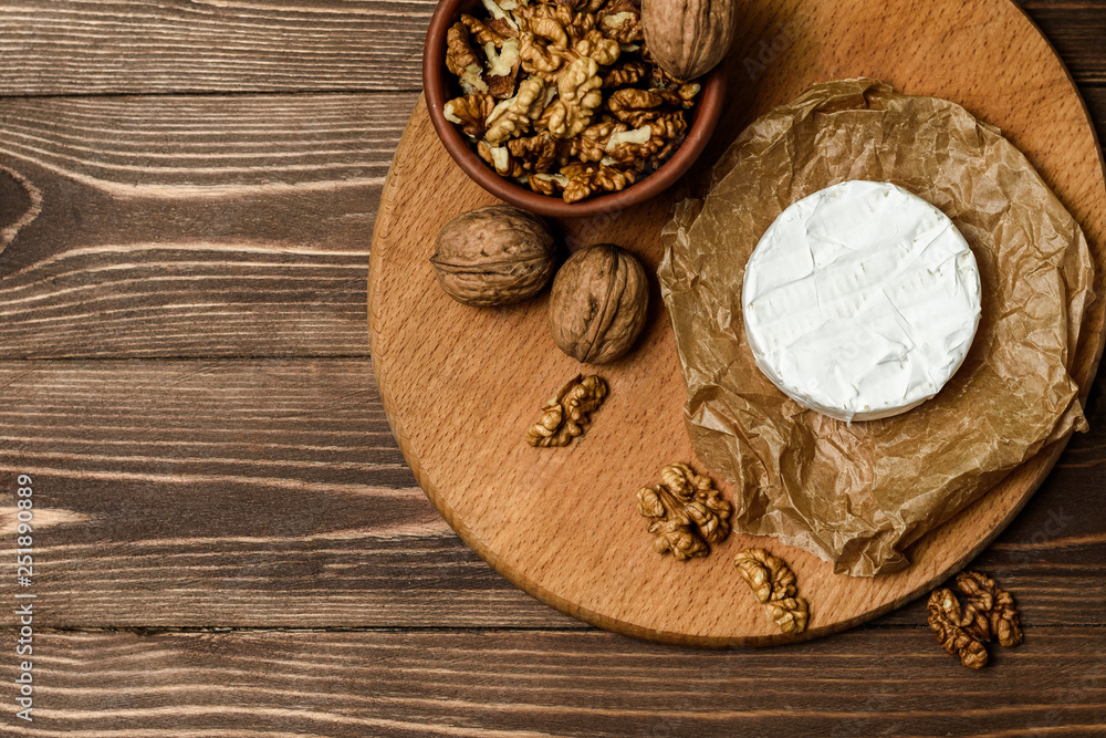 Camembert or Brie cheese with walnut kernels on wooden wooden background. Copy space. white mold grows on top Penicillium camemberti. Camembert or Brie cheese with walnut kernels on wooden wooden background. Copy space. white mold grows on top Penicillium camemberti.