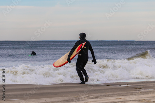 Canvas Print Surfer running into the ocean in a wetsuit