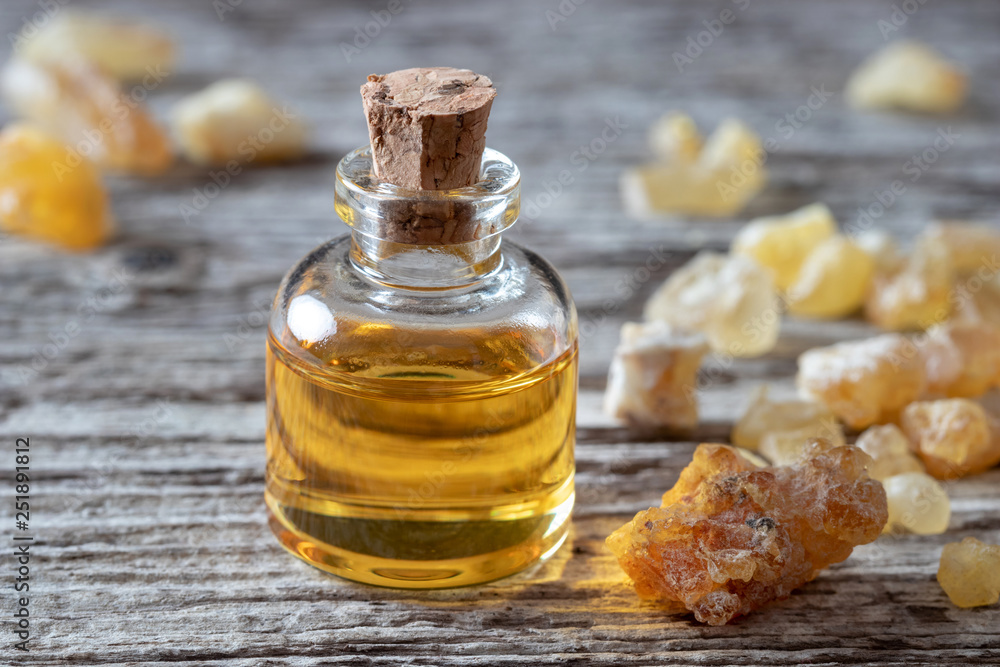 A bottle of frankincense essential oil with frankincense resin crystals A bottle of frankincense essential oil with frankincense resin crystals