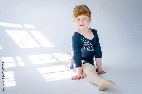 Little girl performs a gymnastic twine in the studio on a white background. The concept of fitness and sport and a healthy lifestyle