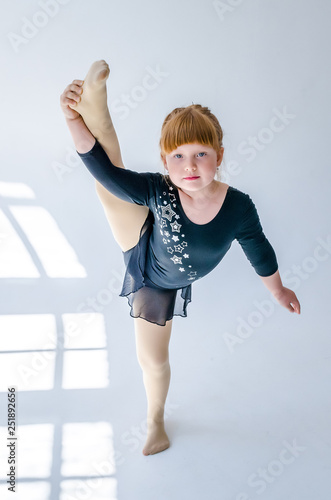 Little girl performs a gymnastic twine in the studio on a white background. The concept of fitness and sport and a healthy lifestyle