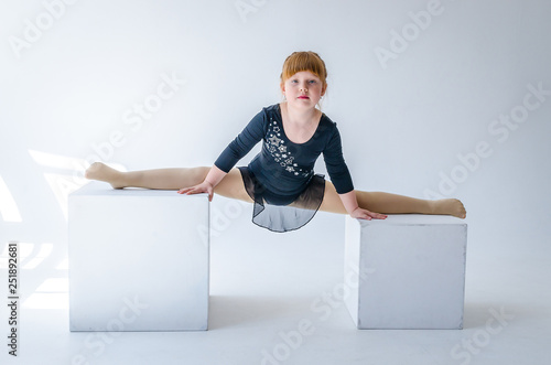 A little girl performs a gymnastic twine in weight. The concept of fitness and sports and a healthy lifestyle. Photo on white background, isolated