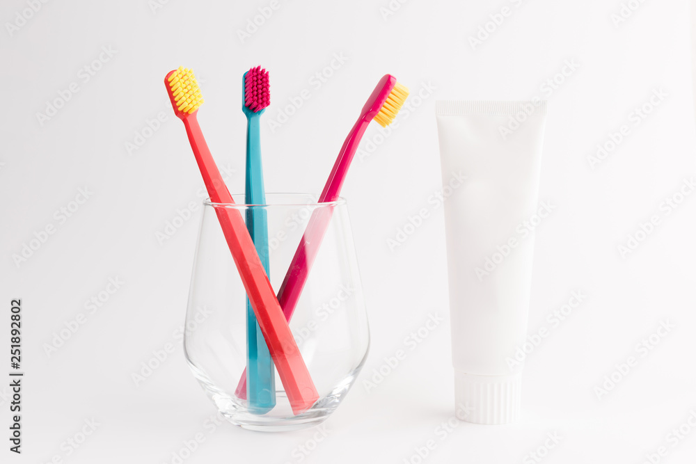 Toothbrushes in glass isolated on pink background with toothpaste tube Toothbrushes in glass isolated on pink background with toothpaste tube